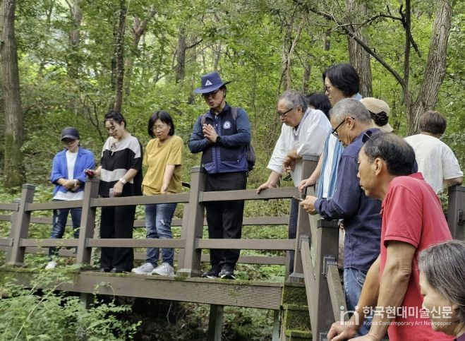 충북 괴산군 성불산 산림휴양단지에서 2025년 숲해설가가 방문객들에게 숲의 생태와 식생에 대해 설명하는 장면