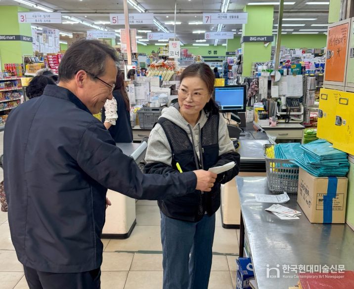 사장이 종량제봉투 주문 수량 확인 후 수령 확인증을 건네 받고 있는 모습